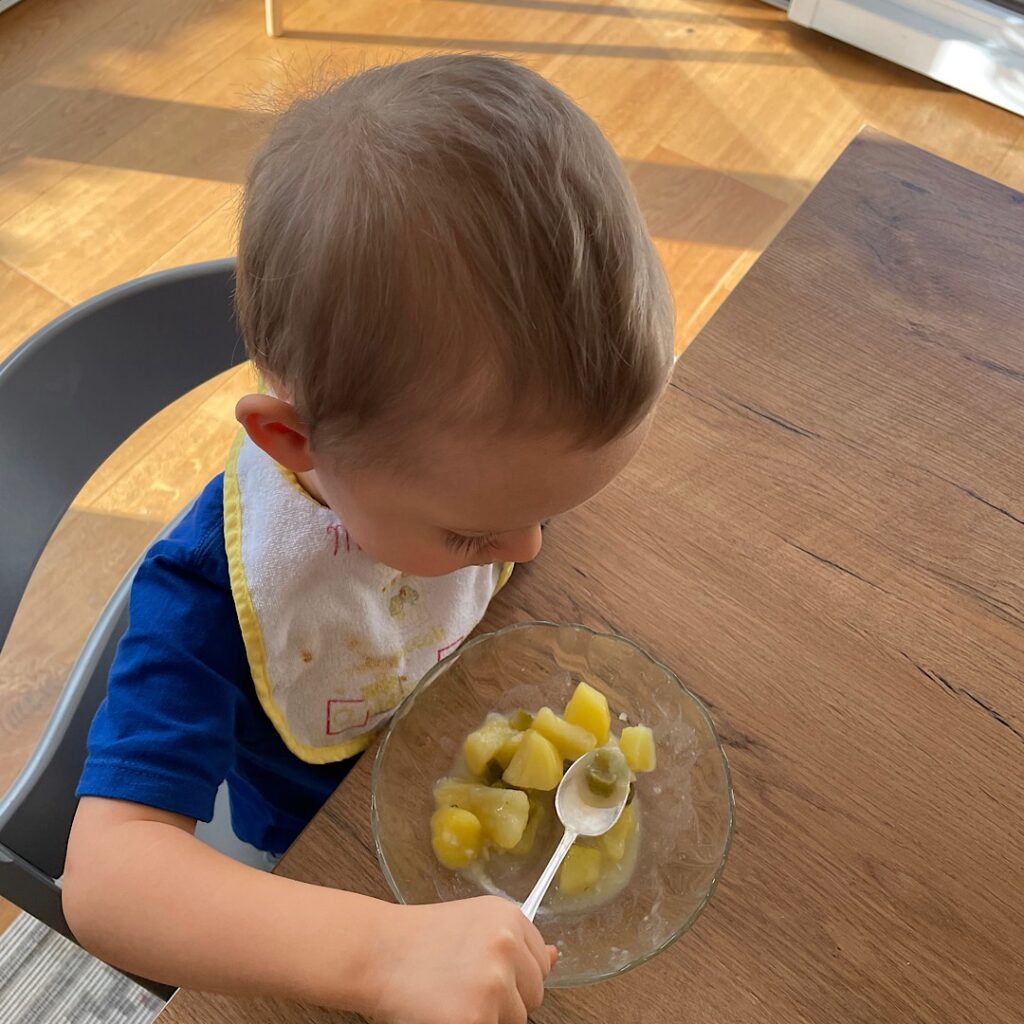 Bub isst Kartoffeln sitzend am Tisch